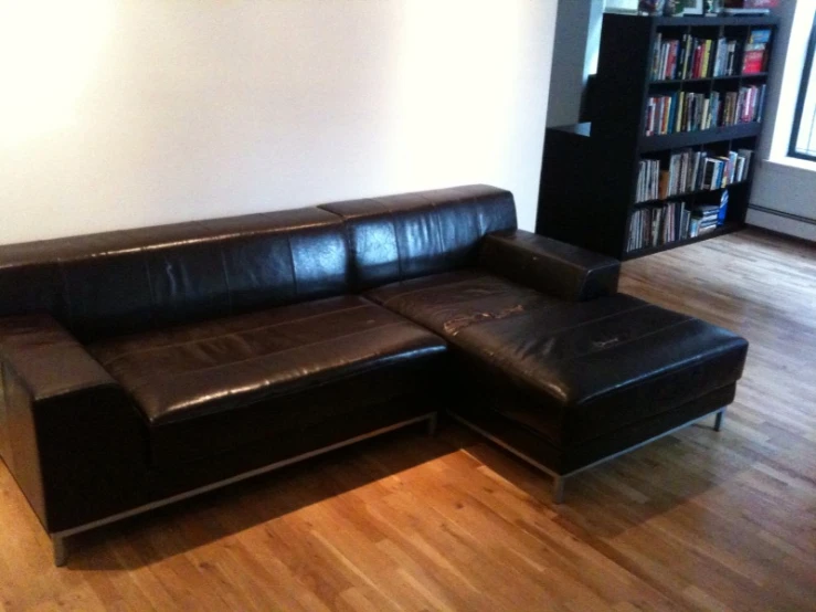 black leather sofa in front of book shelves with wooden flooring