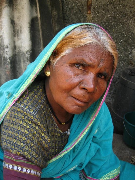 an old woman with white hair wearing a blue shawl