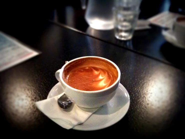 a cup of coffee sits on a saucer at a restaurant table