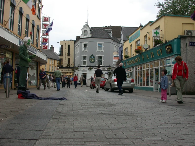 people walk down a street as pedestrians walk past