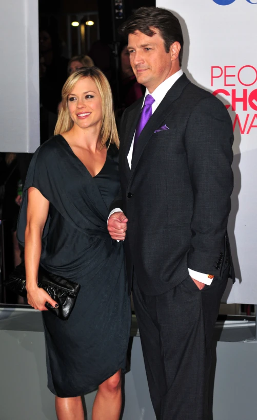 a man and woman standing next to each other in black dresses