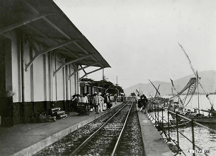 a train station filled with lots of passengers next to the ocean