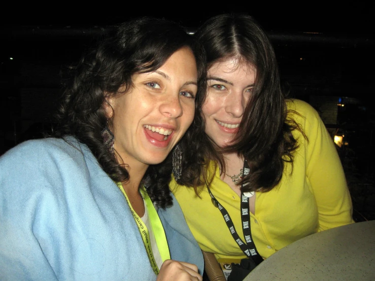 two young women with bright yellow shirts are smiling at the camera