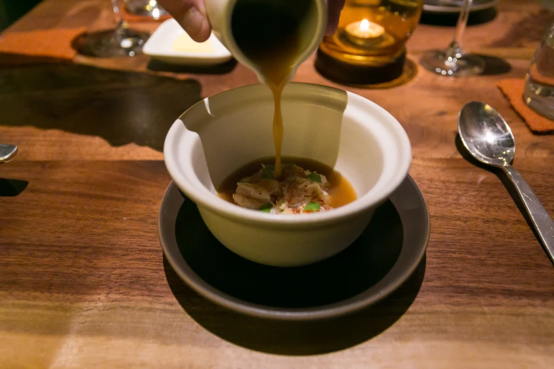 the bowl of soup is being poured with a drizzle of orange sauce