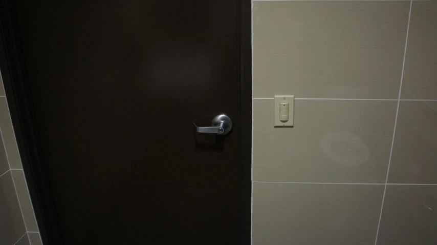 a black and white bathroom door with a toilet paper dispenser