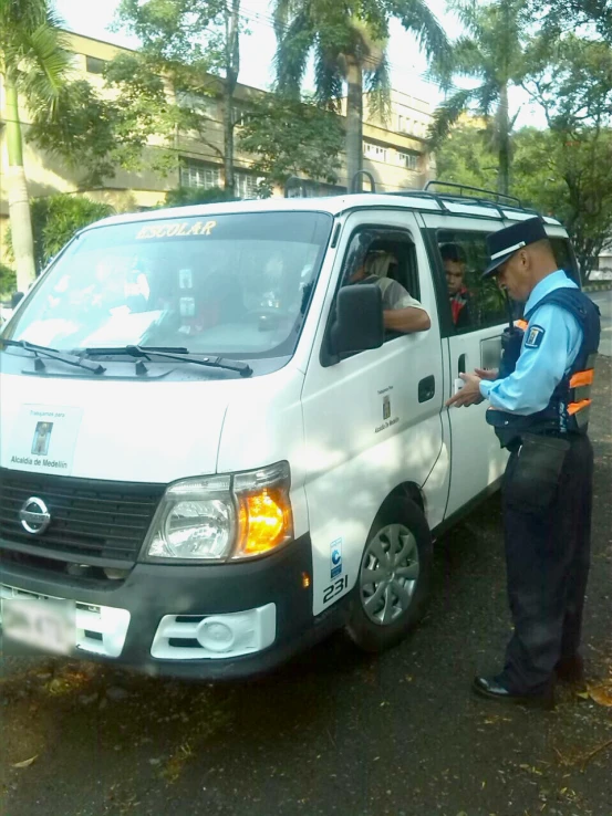 two men talk with each other next to a small white vehicle