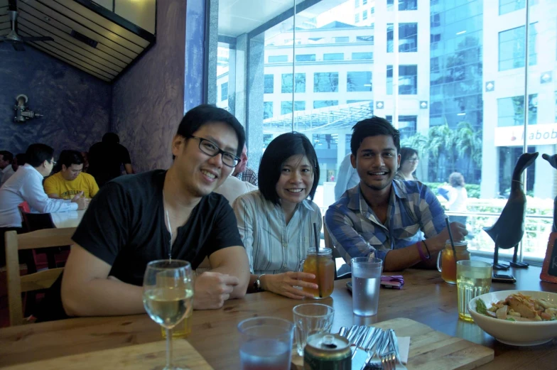 three people are sitting at the table with drinks