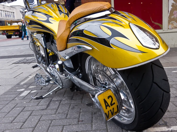 a yellow motorcycle is parked on a brick sidewalk