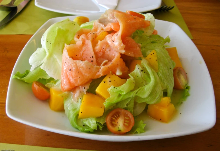 a big plate is full of salad topped with fish