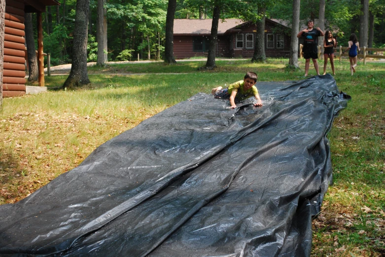 a boy is laying on a tarp with another  walking by