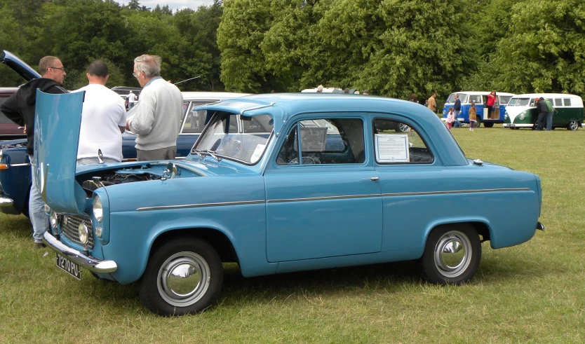 a group of people looking at a vintage car