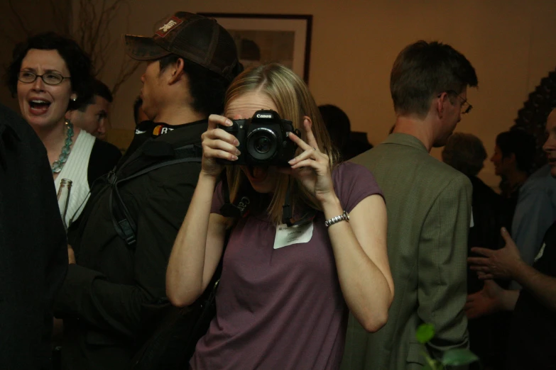 a woman standing in front of a camera next to a man