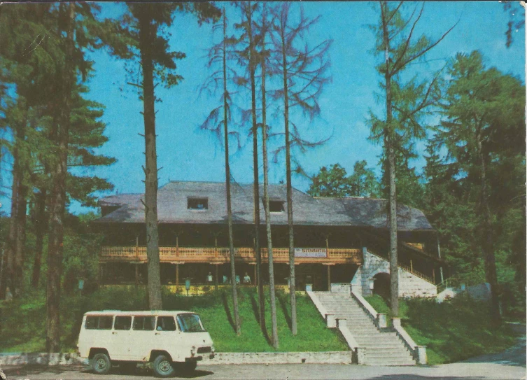 a white van and white car parked in front of a tree lined lodge