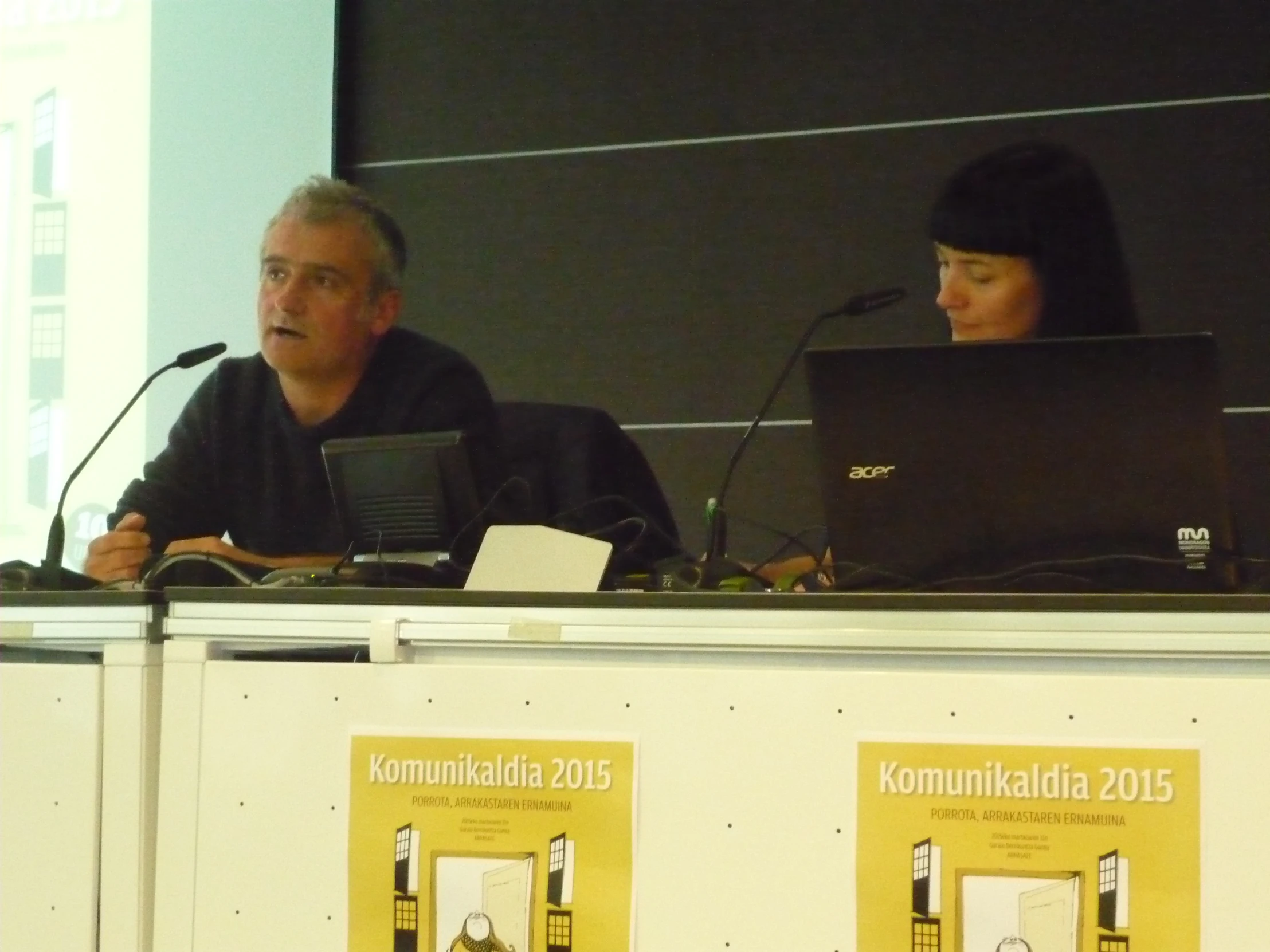 a man and woman sitting at table with computers