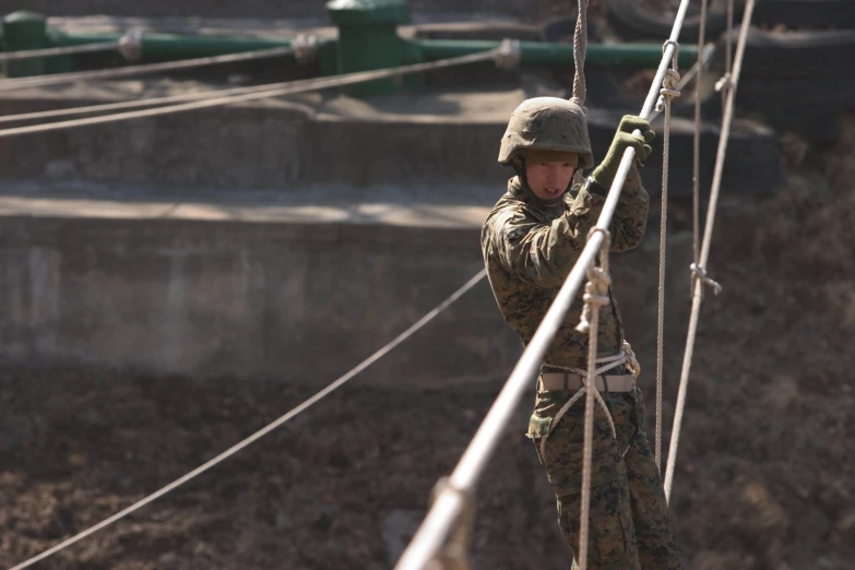 soldier climbing rope, with a background of other structures