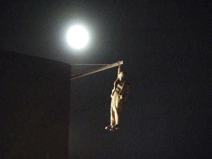 a statue is flying by a full moon in the sky