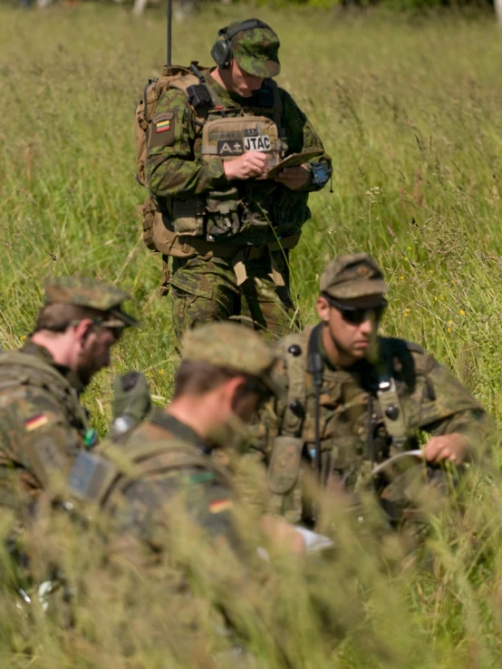 a group of men in army uniforms laying in the grass