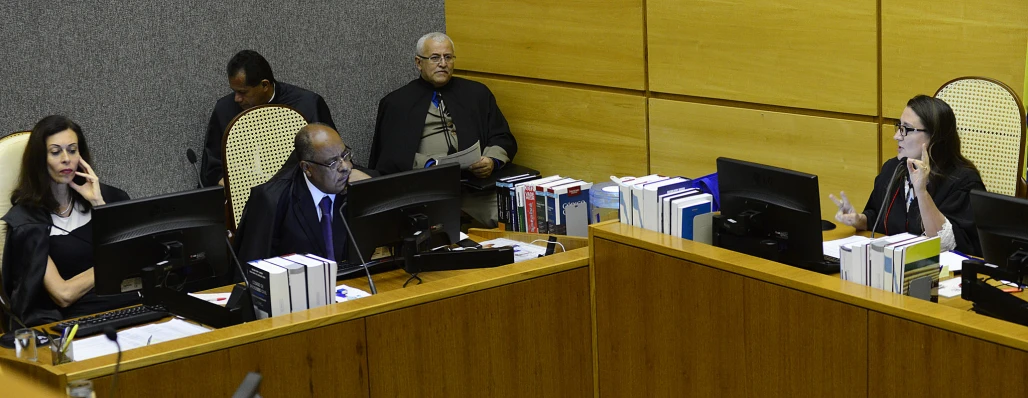 three people in suits are sitting at desks