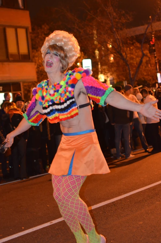 a woman with a clown costume and headdress is dancing in a street