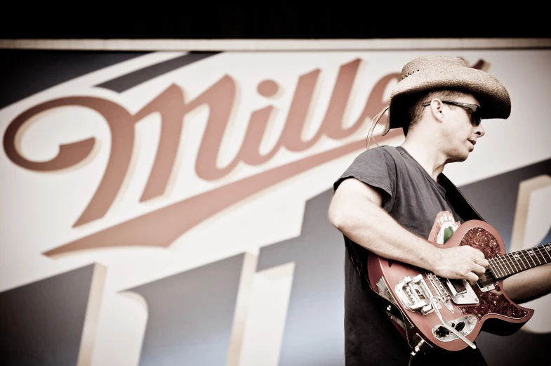 a man with a hat and glasses plays an electric guitar