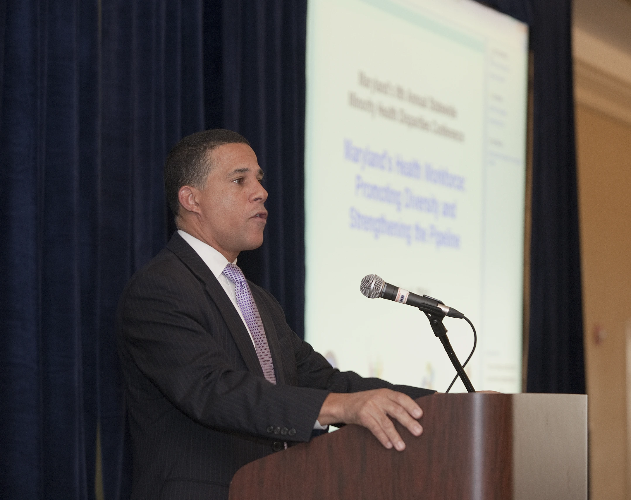 a man wearing a suit is speaking from a podium