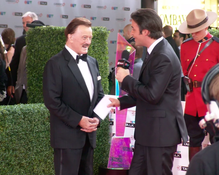 two men talking to each other at a red carpet