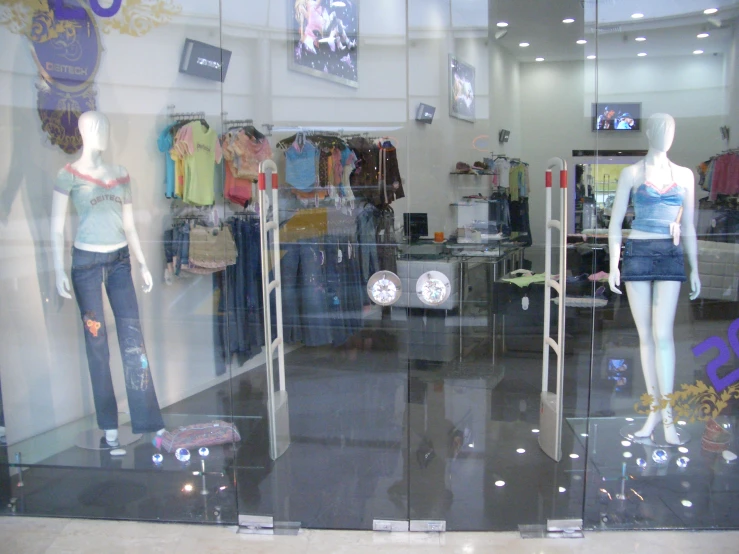 three mannequins in a window with clothes and footwear