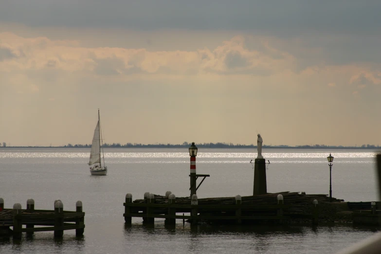 a sailboat is sitting in the water near a pier