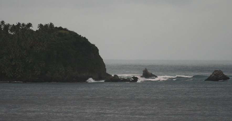 a lone bird stands on top of the rocks at the edge of a body of water