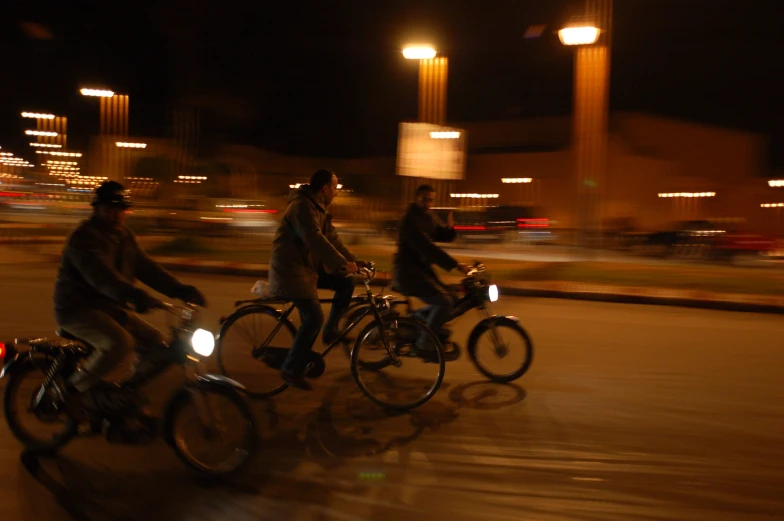 people riding bicycles down a street at night