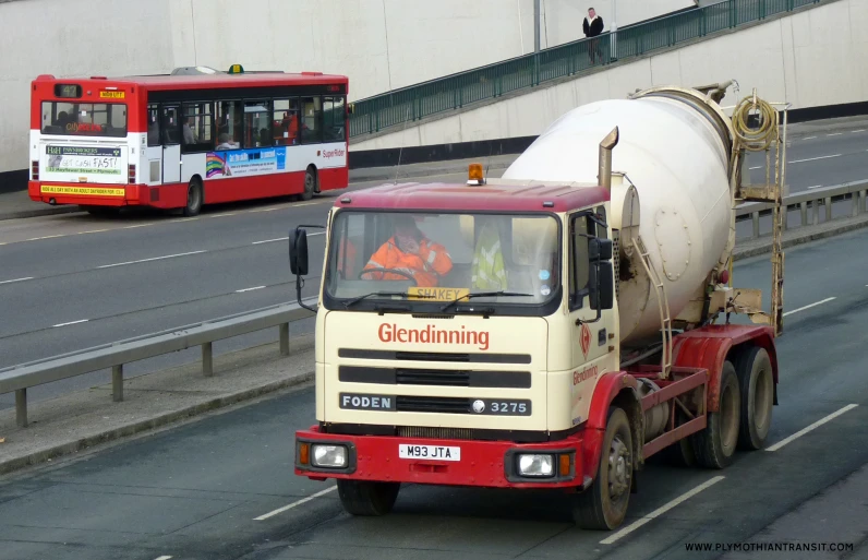 an old red and white tanker truck driving down the road