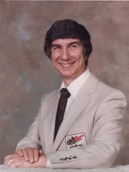 a man in a white suit and tie posing for a picture