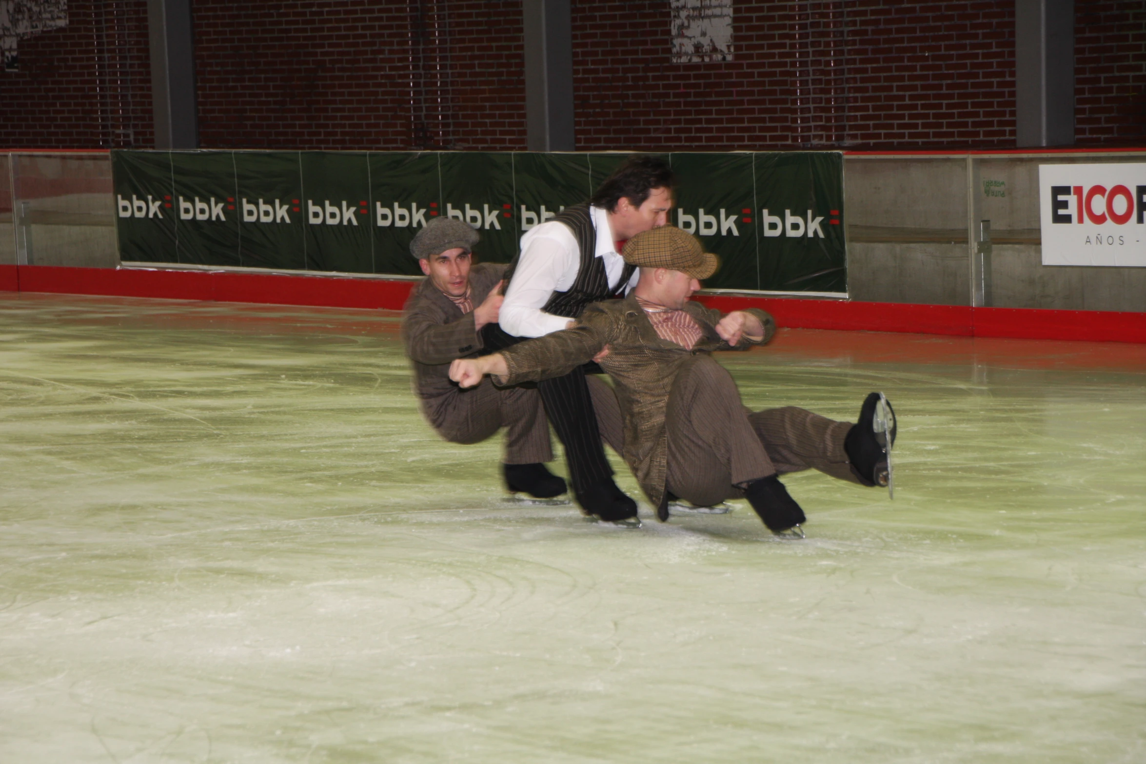 three men in kilts standing on one another ice skating