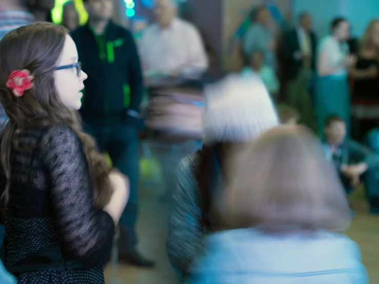 the girl is talking and watching people stand around in a room