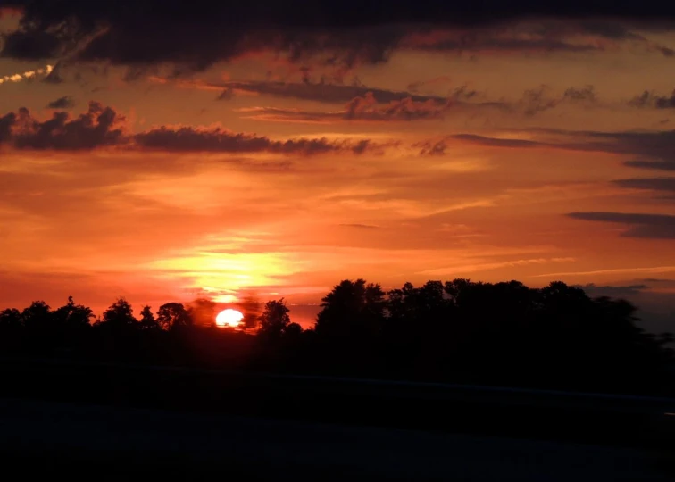 the sun setting in a cloudy sky as seen from a train