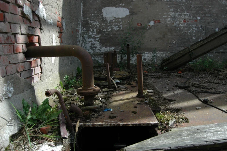 an abandoned building with pipes protruding out of the ground