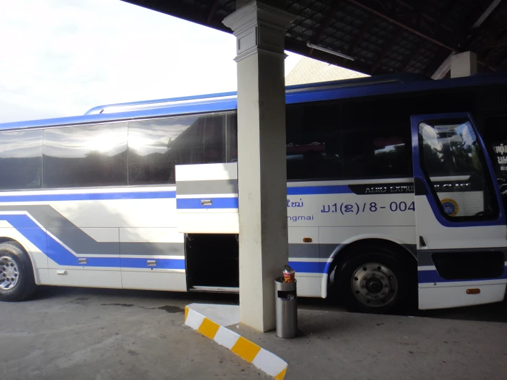 a white and blue bus parked underneath a pavilion