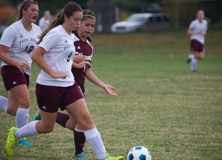 two girls running and playing soccer in a field