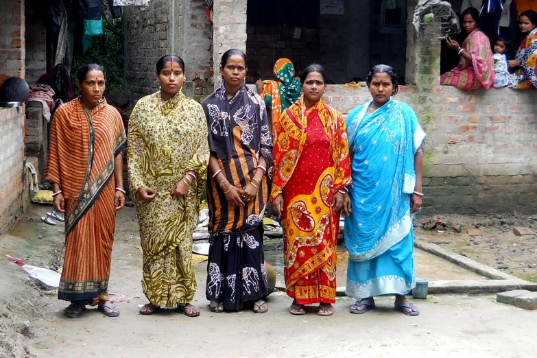 women dressed in brightly colored clothing pose for the camera