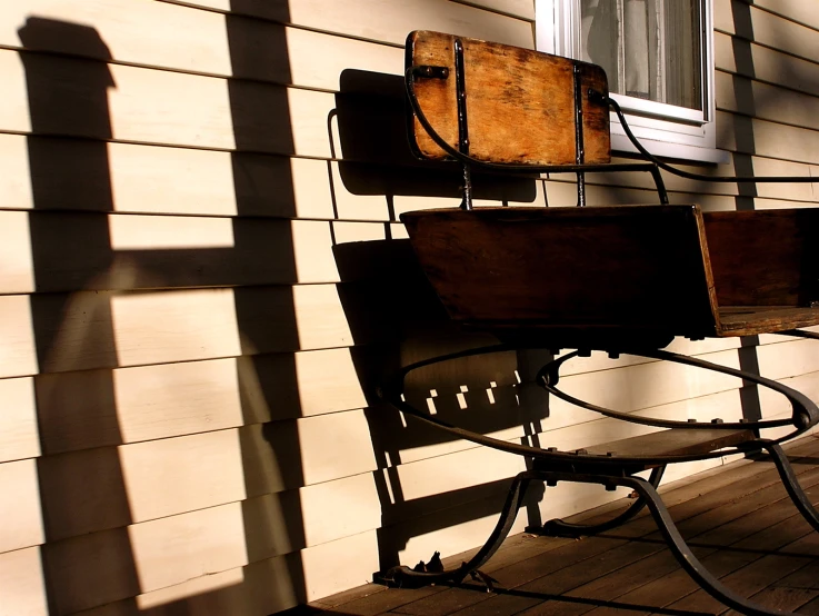 the shadow of an iron and wooden chair on a house