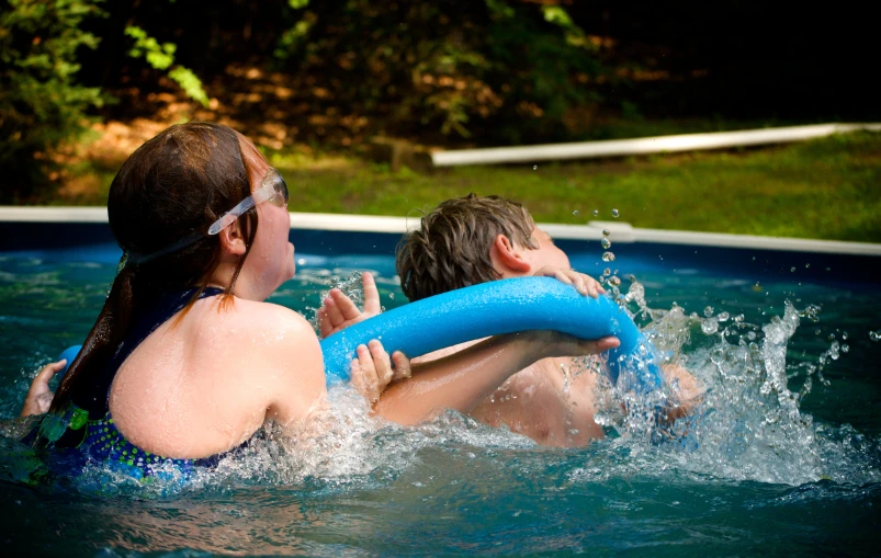 a couple playing in the pool with a blue pool float