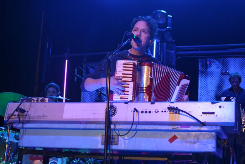 the man is playing an accordion while singing into the microphone