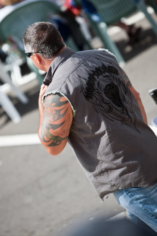 man with tattoos sitting on a motorcycle outdoors