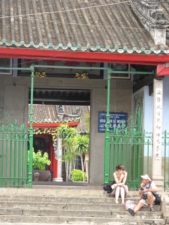 a woman sitting on the step by the entrance to an oriental store