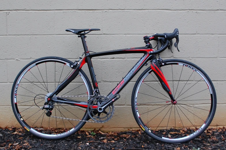 the red bike is leaning against a brick wall