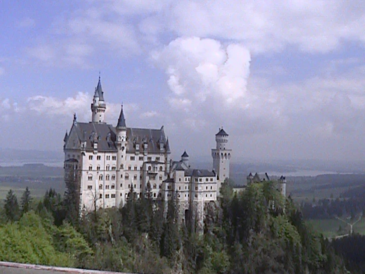 a castle is seen above the greenery on a sunny day