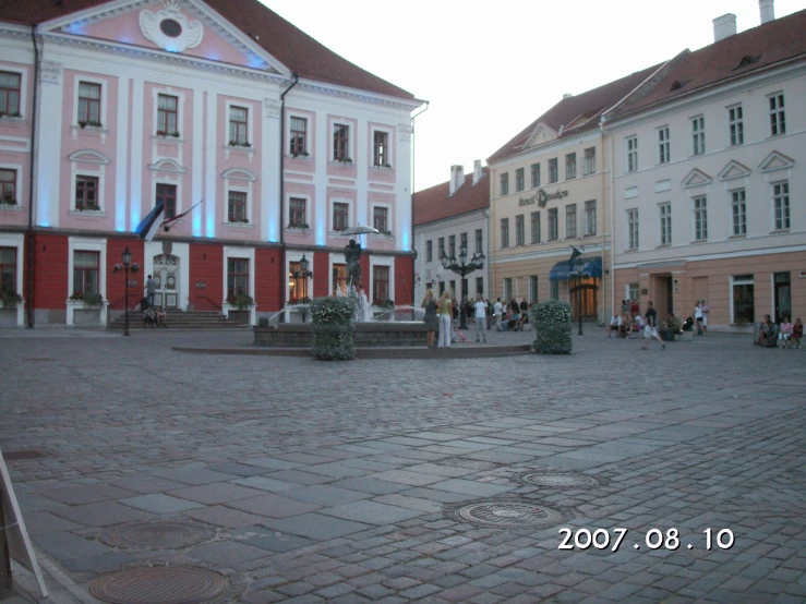 people walking around in front of a few pink buildings