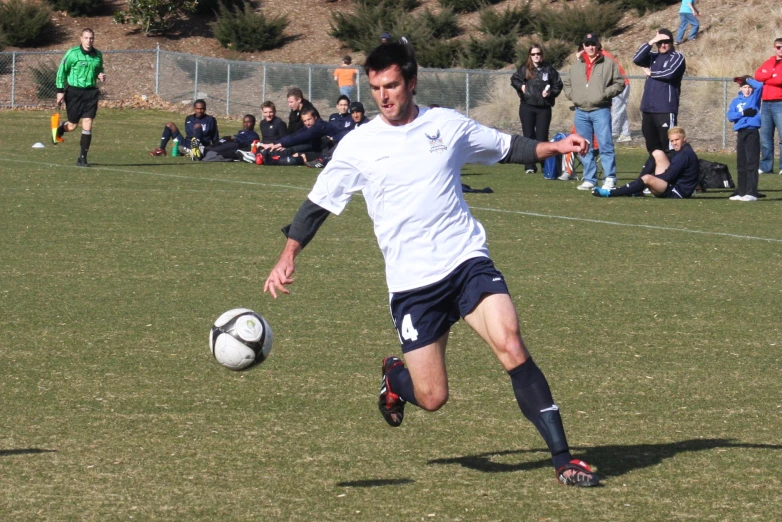 a man kicking a soccer ball around on a field