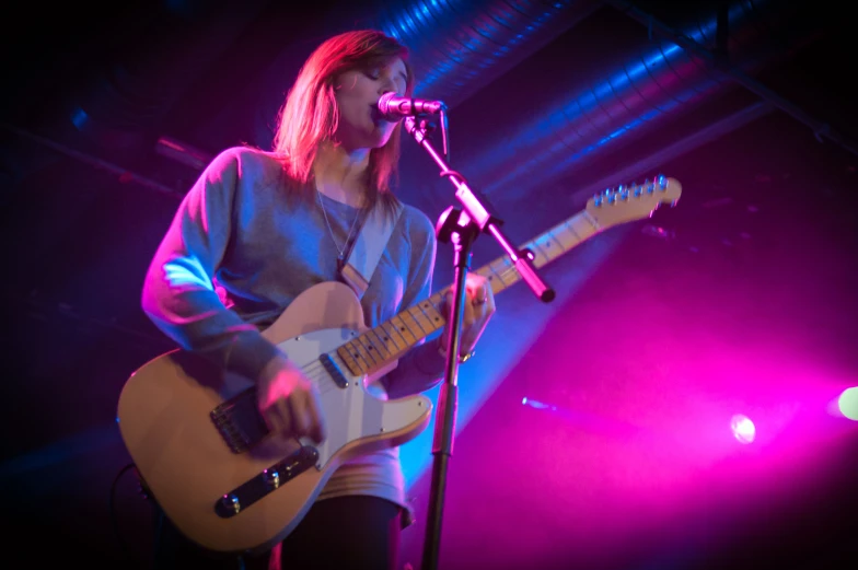 a woman on stage playing a guitar and microphone