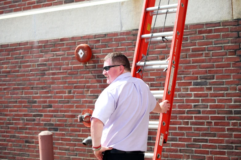 man in white shirt and sunglasses standing on red ladder